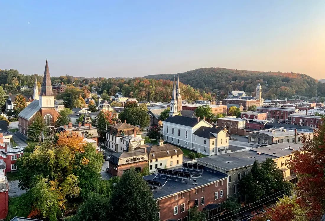 A small town of brick blocks, church steeples and autumn trees, lit by the low sun
